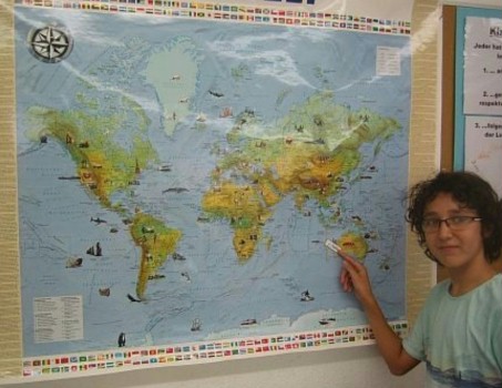 Schüler steht vor einer Weltkarte und zeigt Indonesien