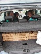 Schüler im Auto, hinten im Kofferraum liegen Pizzakartons.