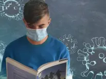 Ein Junge trägt eine Maske und liest ein Buch.