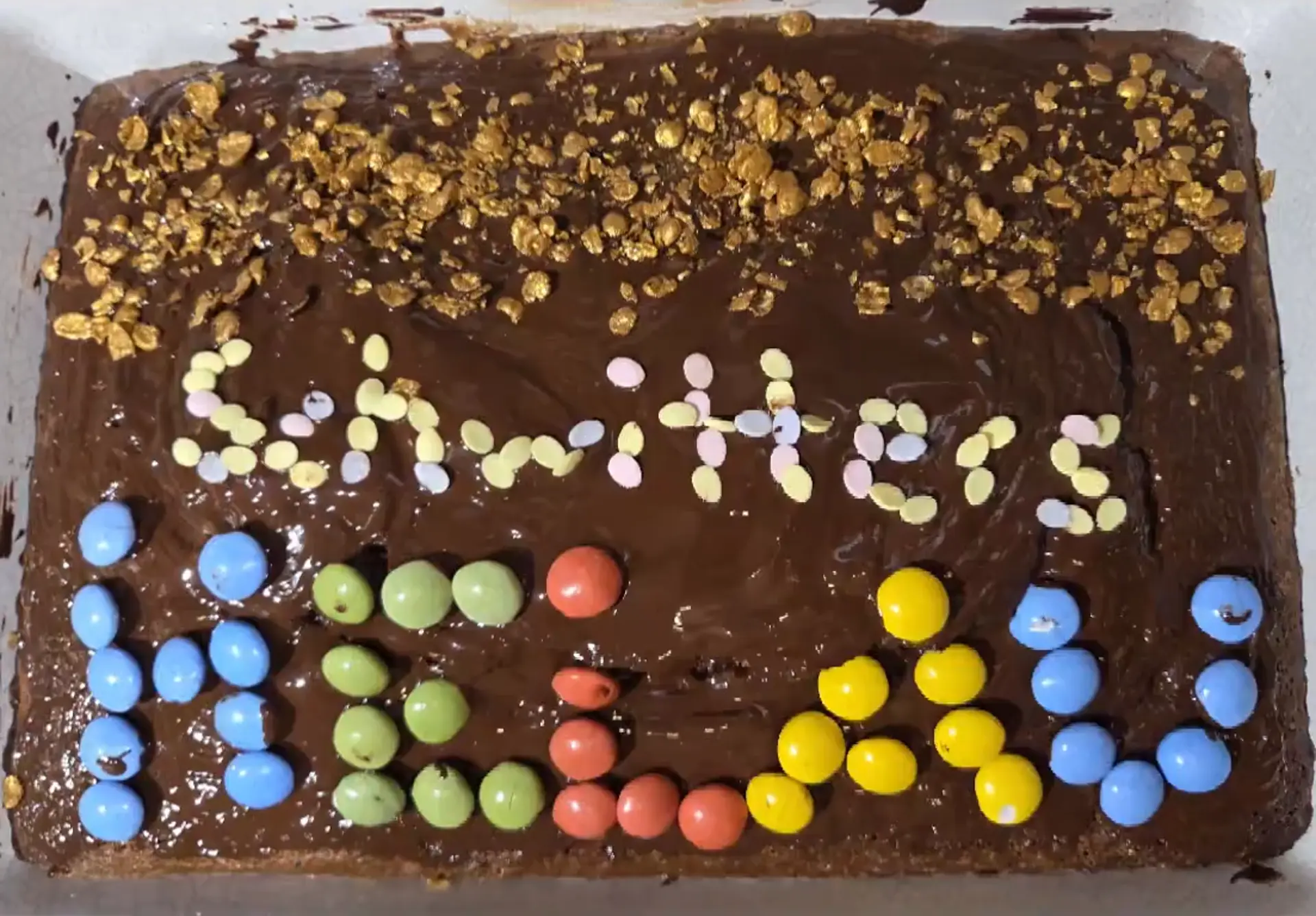 Ein Kuchen mit Schokoglasur. Mit bunten, runden Bonbons steht "Schwitters Helau" geschrieben.